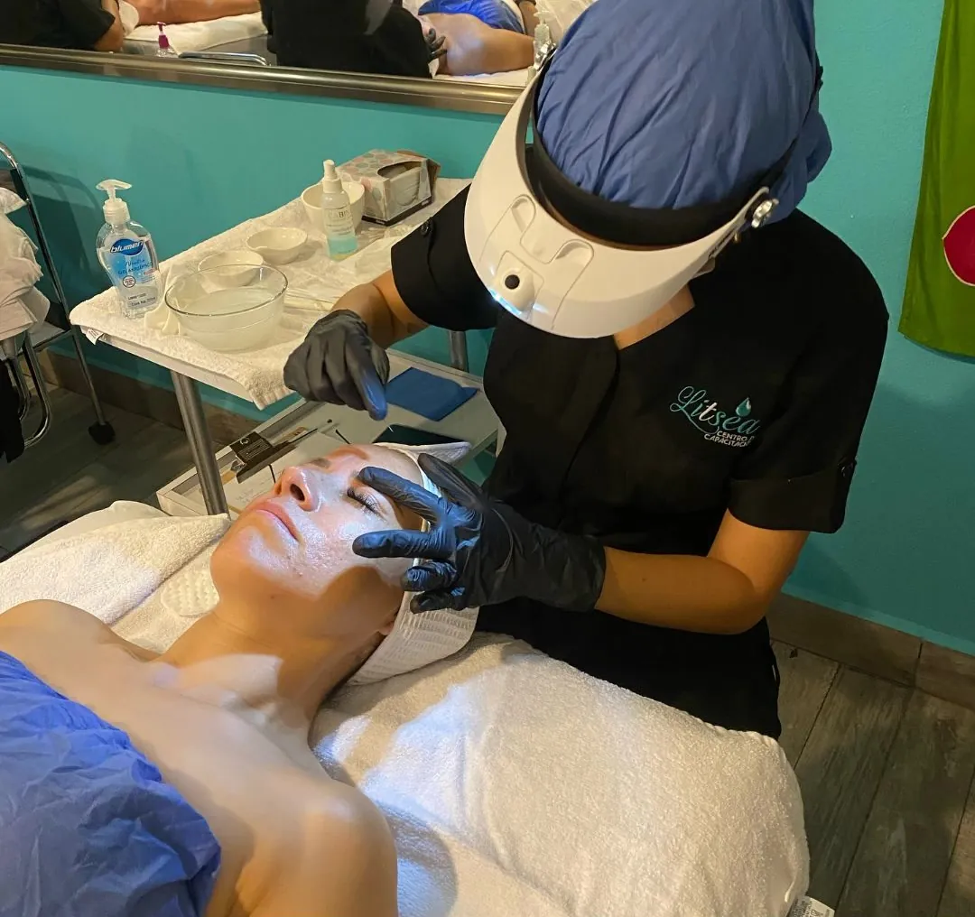 Alumna con careta y guantes realizando un tratamiento facial en cabina