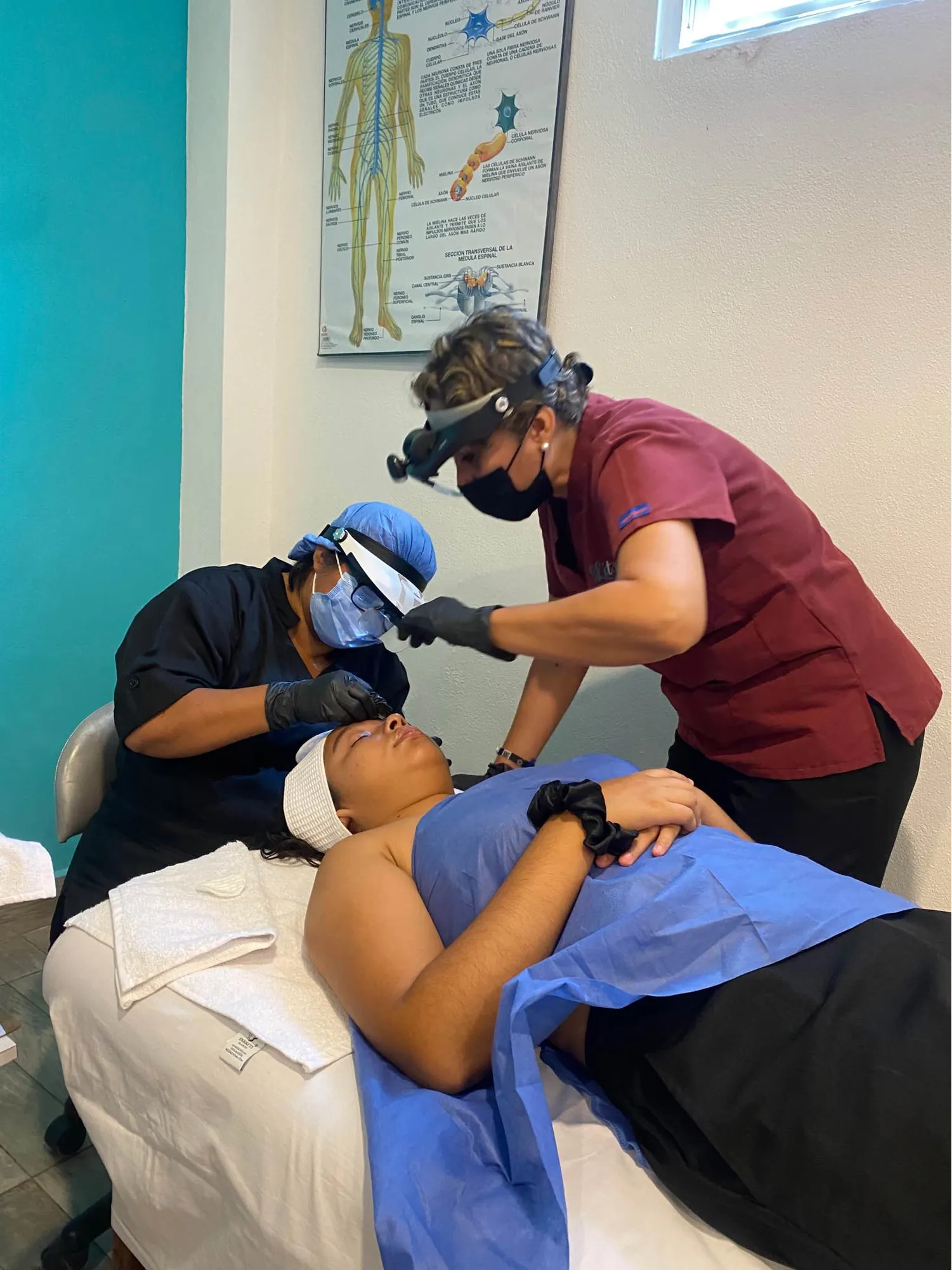 Alumna de cosmetología con lupa en un tratamiento facial mientras su maestra la supervisa