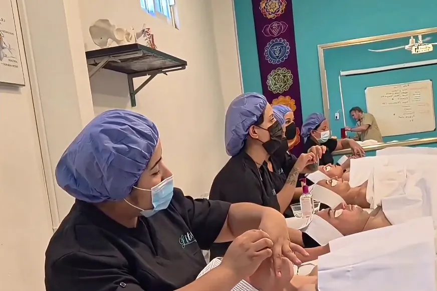 Alumnas de cosmetología trabajando en una fila de cabinas